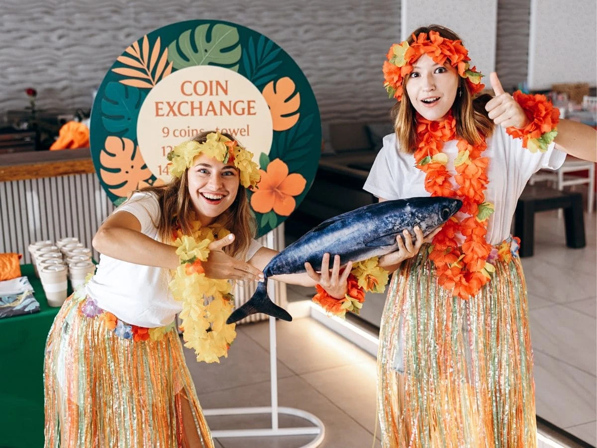 Two entertainers in Hawaiian costumes holding a fish at a tropical party
