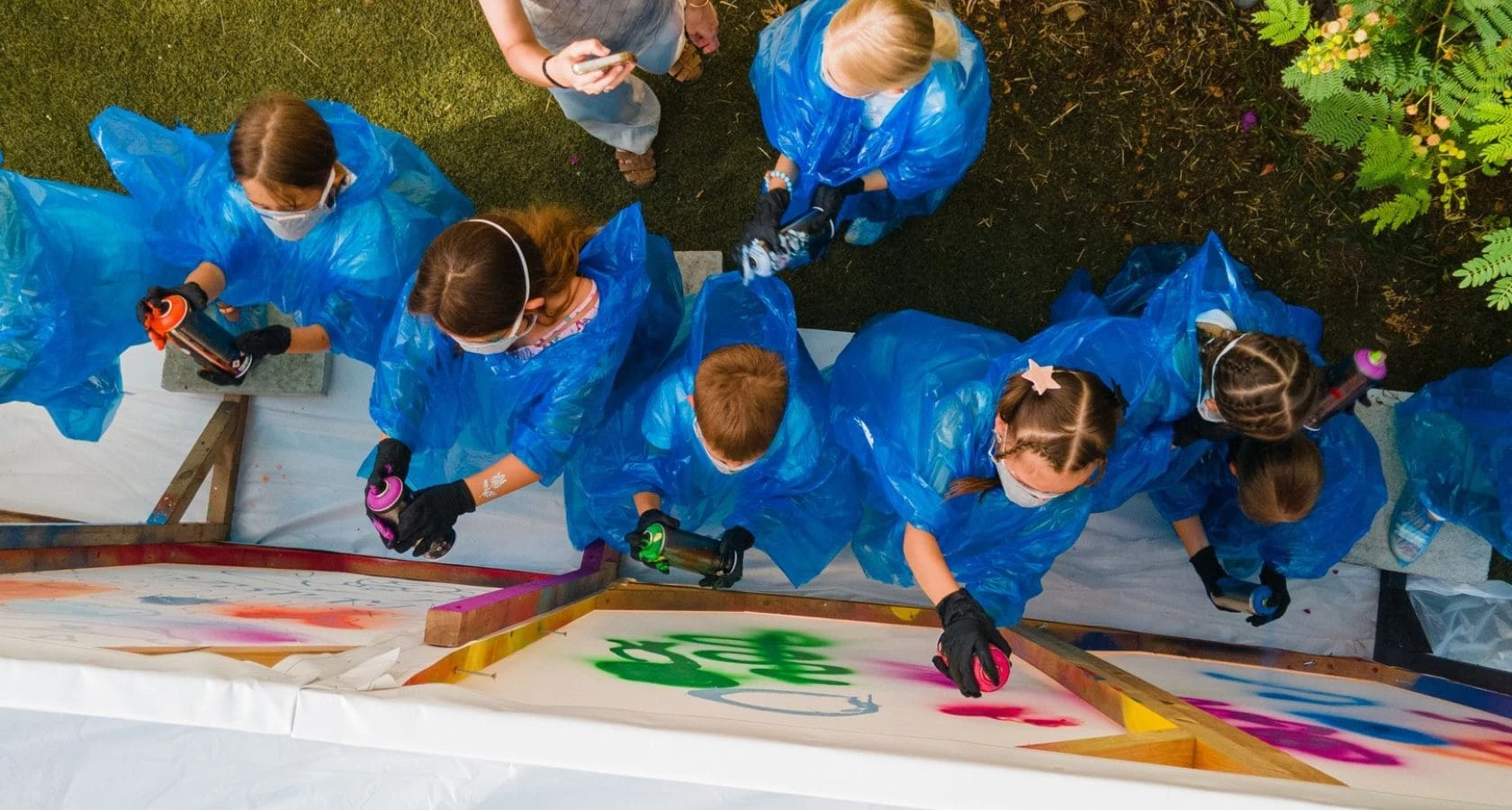 Children painting with spray cans at an outdoor workshop