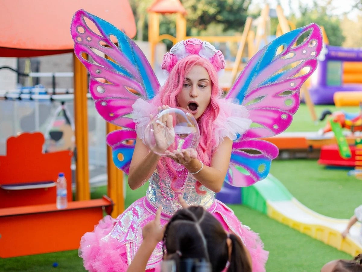 Fairy entertainer performing a bubble show for children at a party