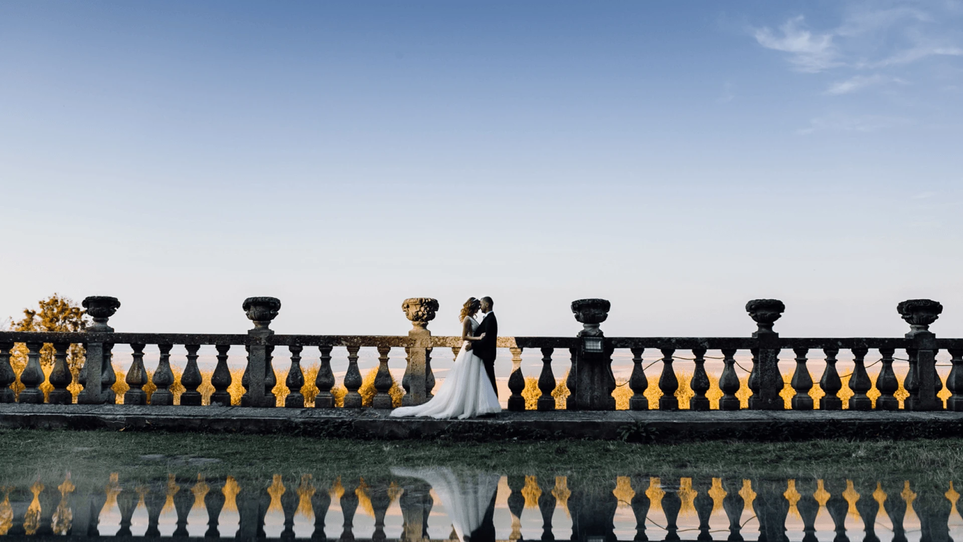 Couple standing at a geometric floral arch during a seafront wedding ceremony at golden hour in Cyprus.