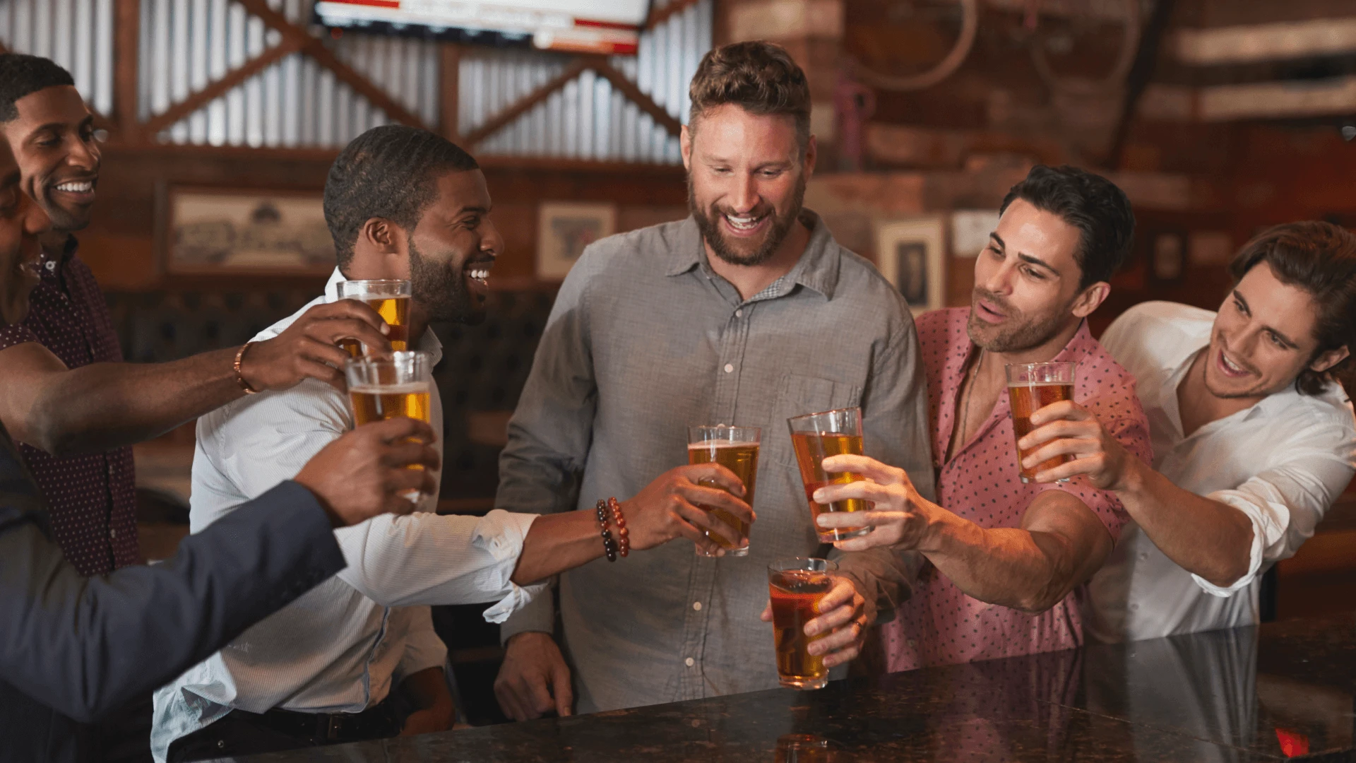 Group of men toasting with beers at a bar during a stag party in Cyprus