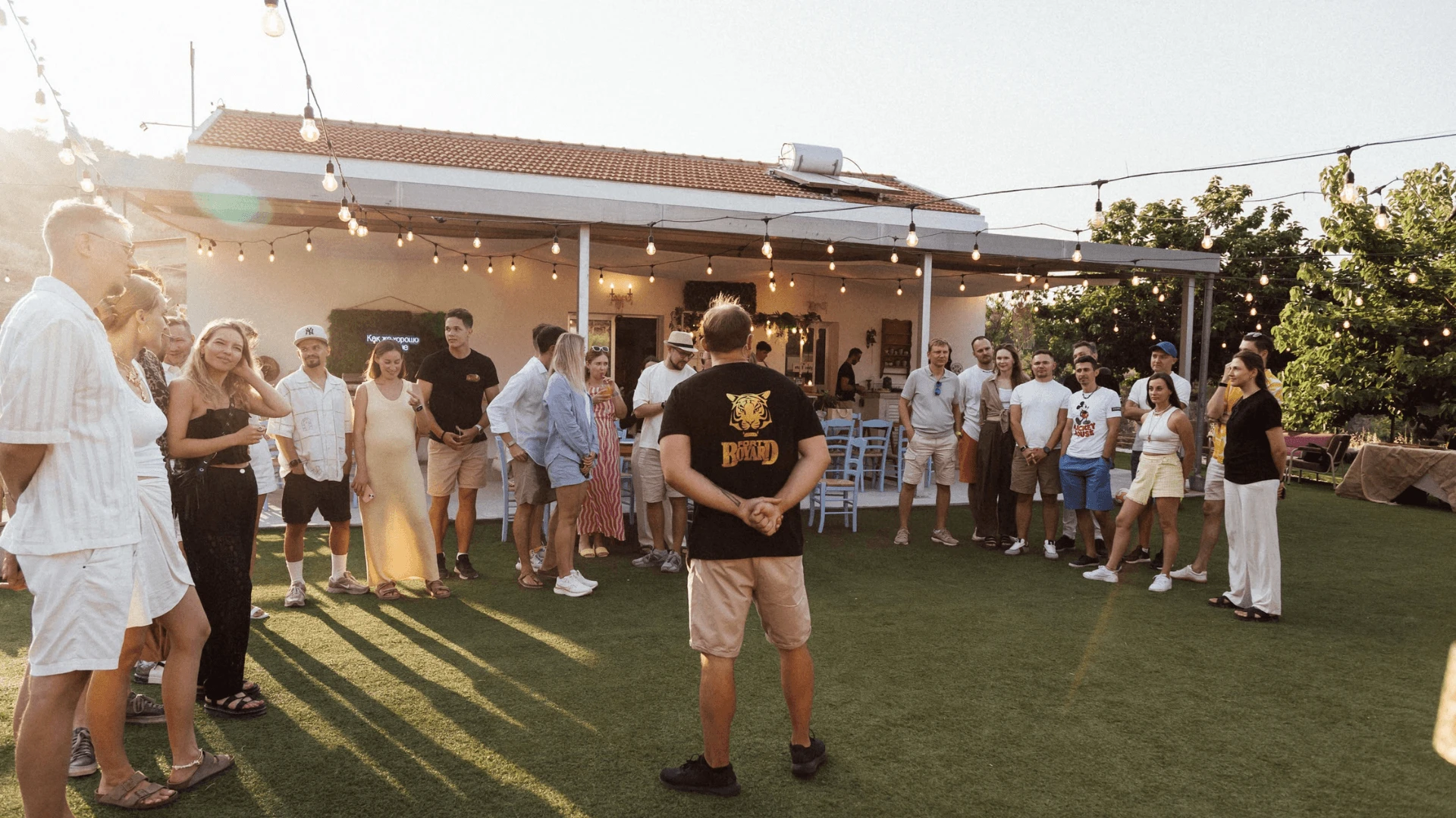 Group standing in a circle on a lawn at sunset as a host briefs a Fort Boyard team building game in Cyprus