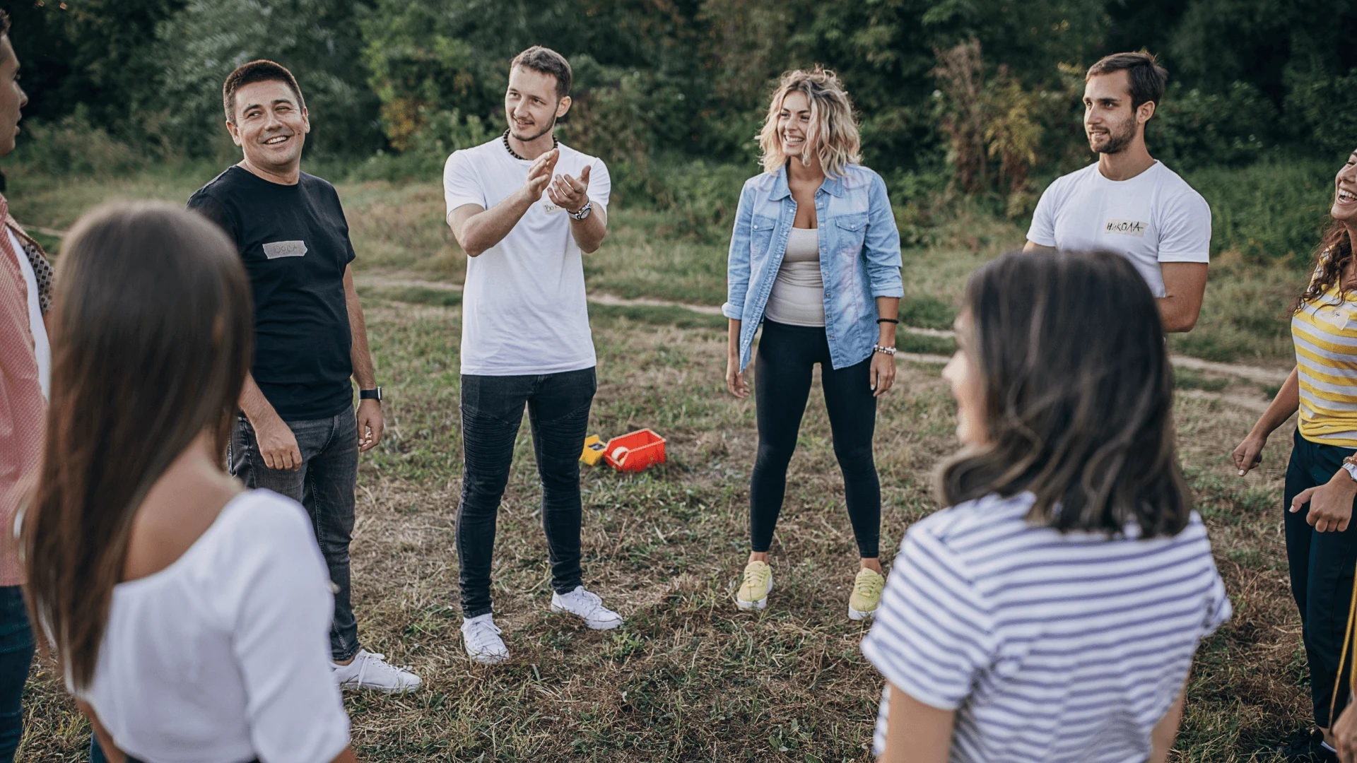 Colleagues standing in a circle laughing during an outdoor team building game in a Cyprus field