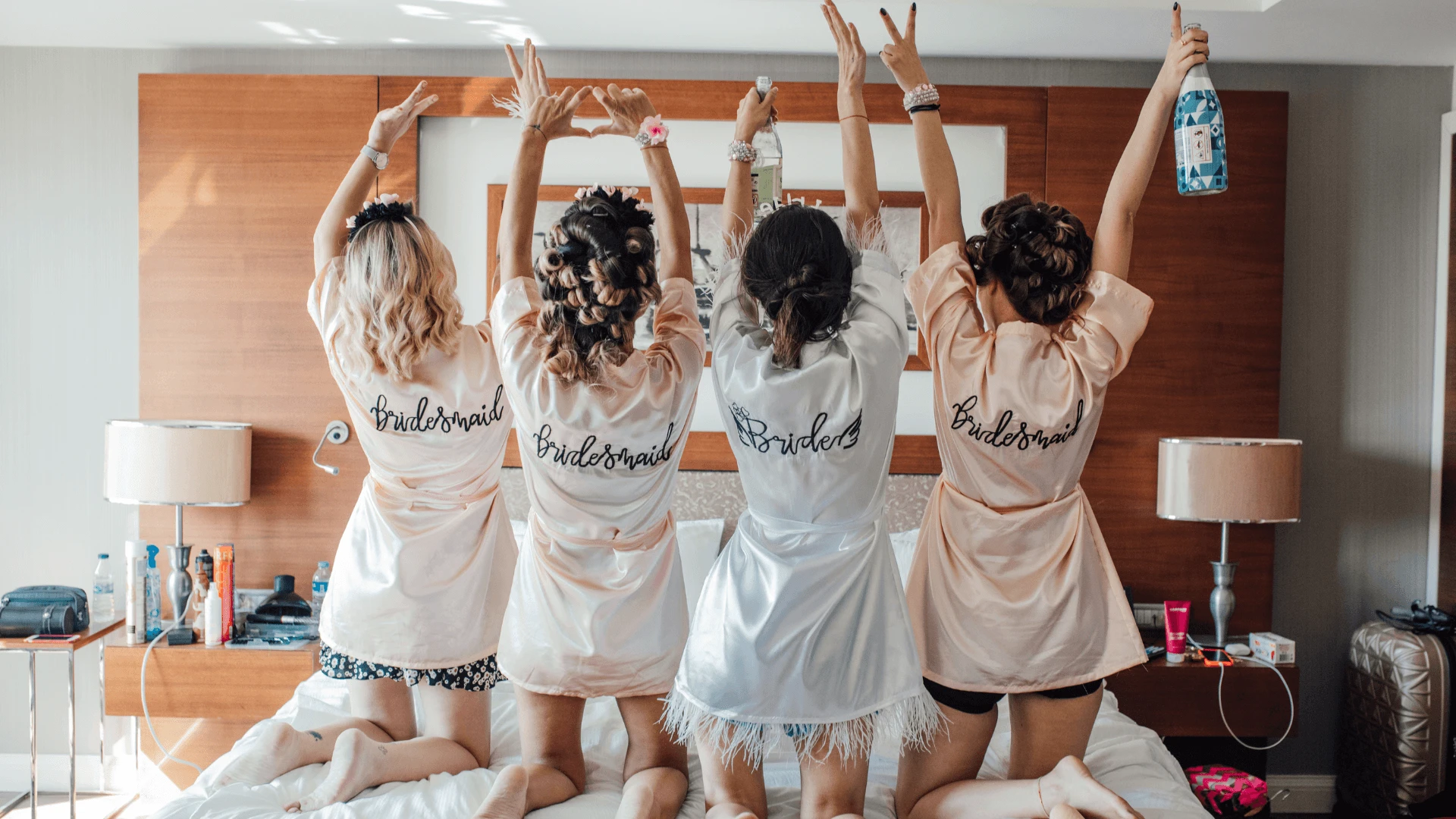 Bride and bridesmaids in matching robes raising arms with a bottle at a hen party in Cyprus