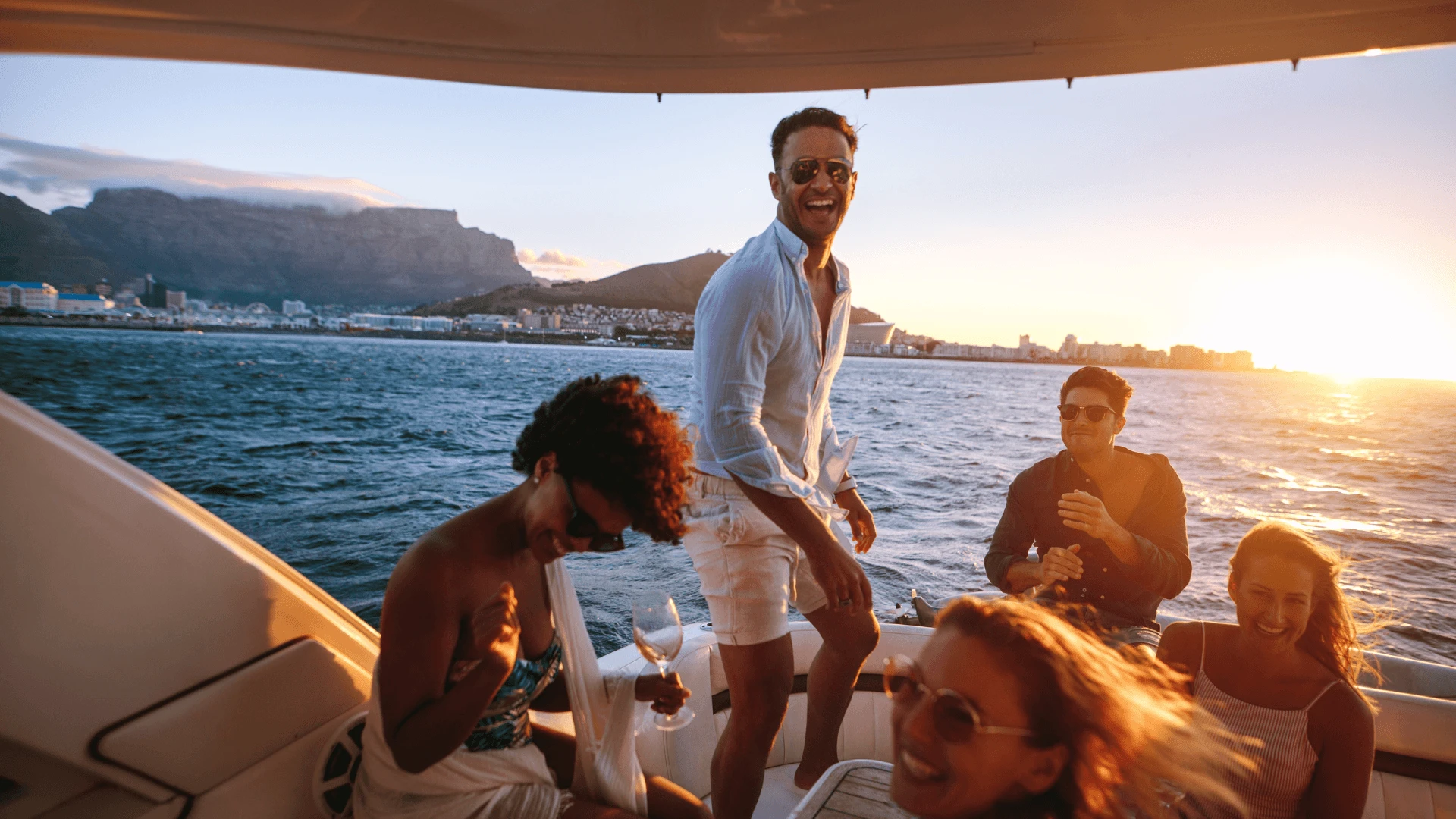 Private yacht party at sunset off the Limassol coast, guests on deck with drinks as the sun meets the horizon.