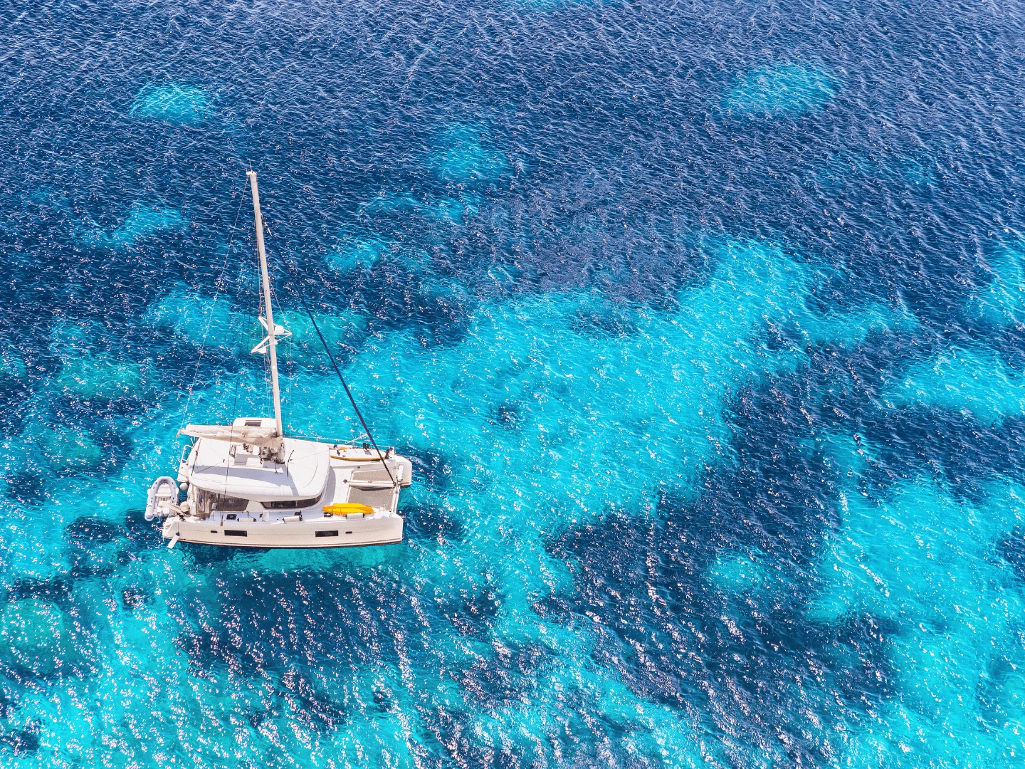 Aerial view of a catamaran anchored on bright turquoise water for a yacht party in Cyprus
