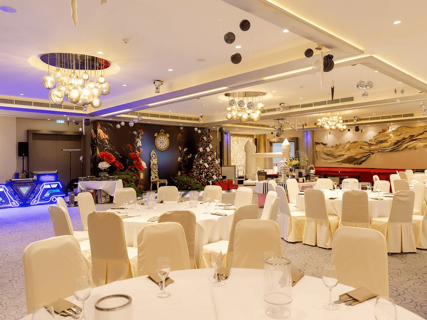 Hotel ballroom laid with round banquet tables, a decorated tree and a themed backdrop before guests arrive