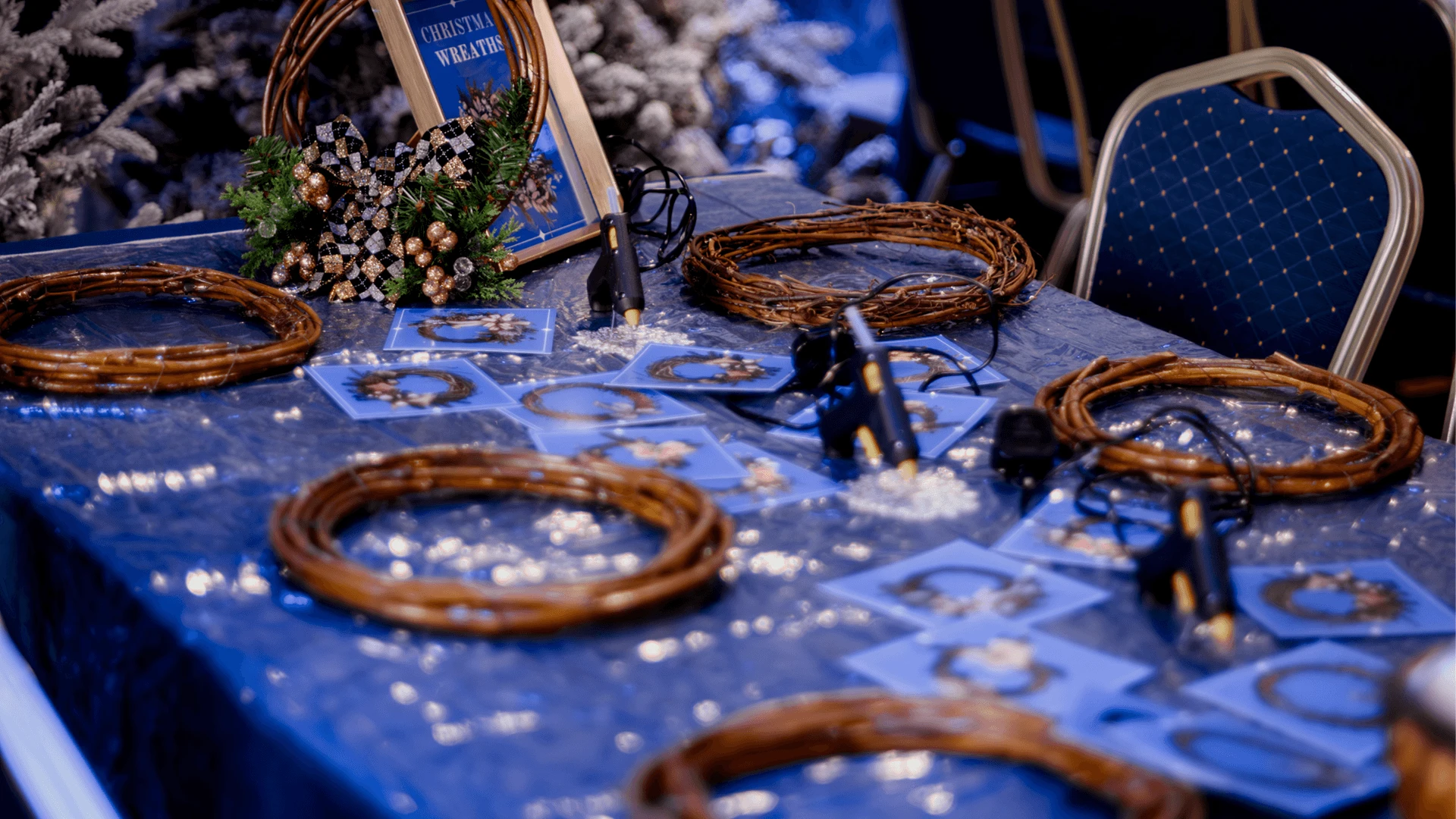 Workshop table set with willow wreath bases, glue guns and instruction cards at a New Year event