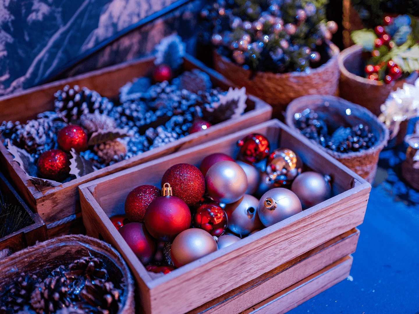 Wooden crates filled with red and gold baubles, pinecones and greenery during event setup