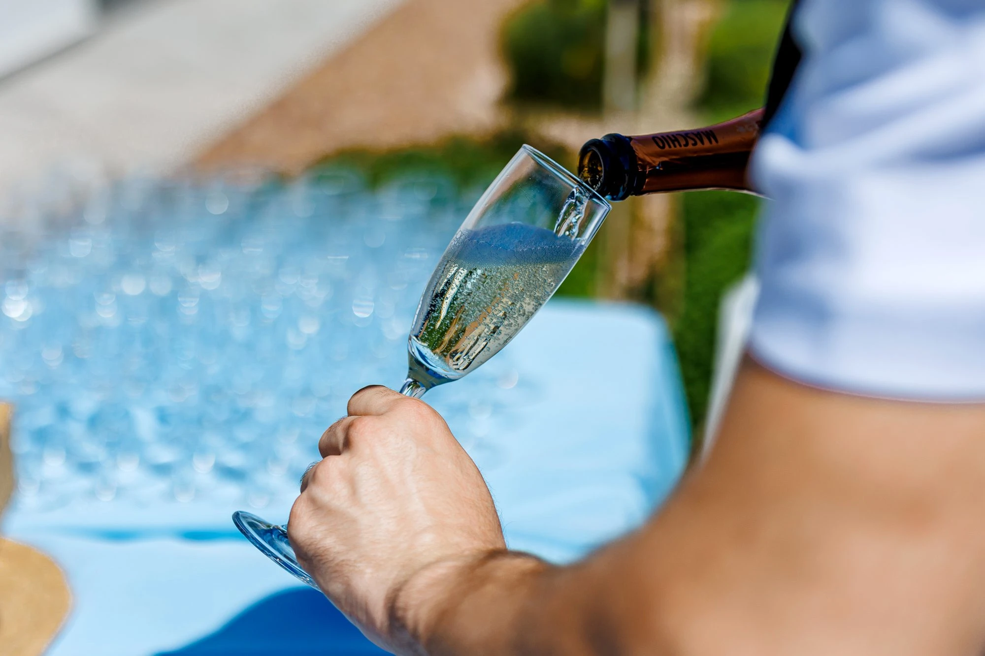A waiter pouring champagne into a glass at a garden party